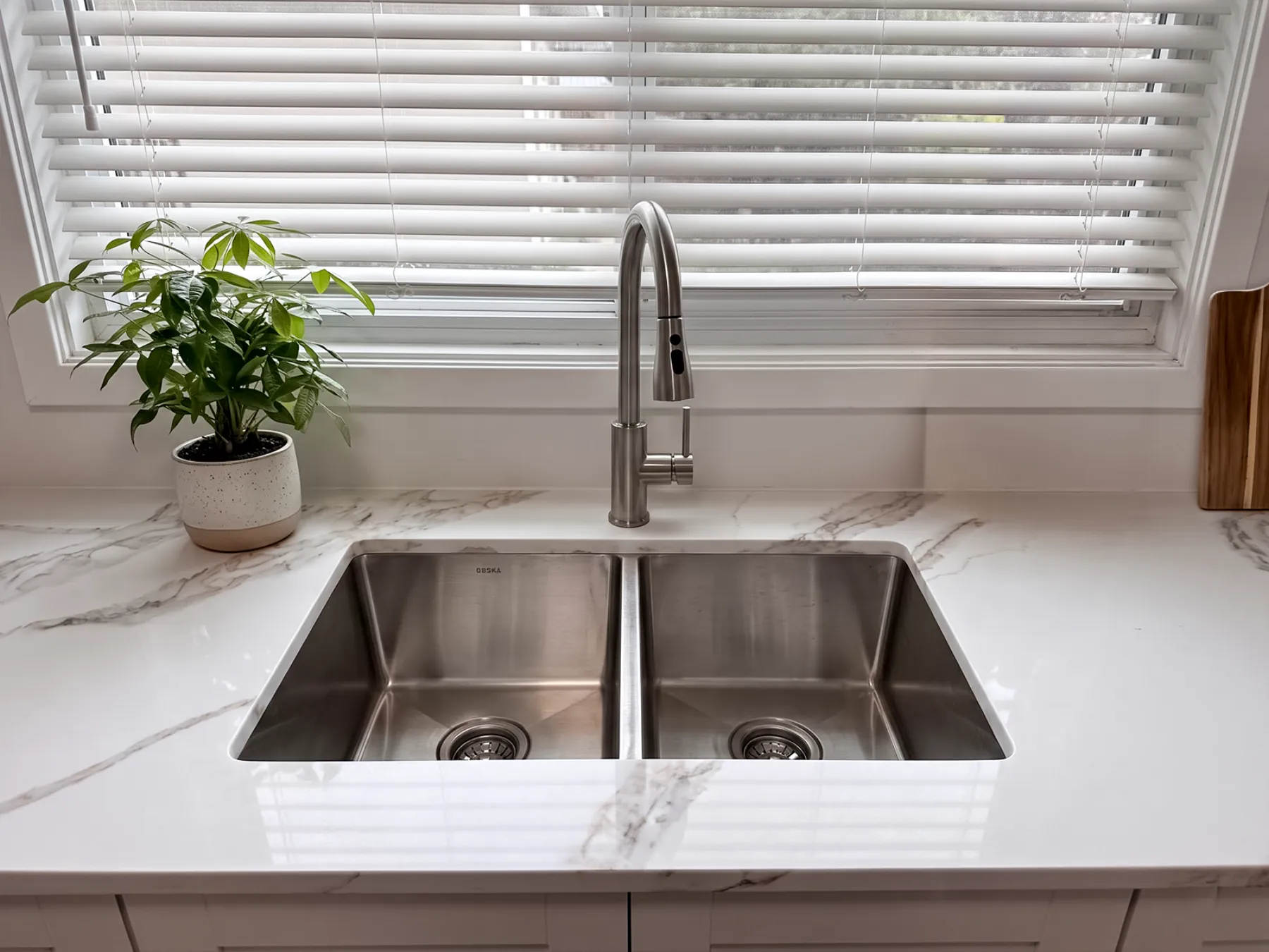Double-bowl undermount sink set into the quartz counter beneath the window